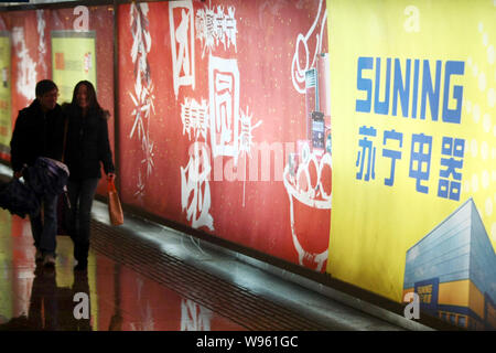 --FILE--Pedestrians walk past an advertisement for home appliance retailer Suning in Shanghai, China, 6 February 2012.   Chinese electronics and home Stock Photo