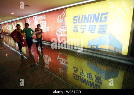 --FILE--Pedestrians walk past an advertisement for home appliance retailer Suning in Shanghai, China, 6 February 2012.   Chinese electronics and home Stock Photo