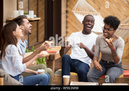 Happy diverse young people eating pizza having fun Stock Photo