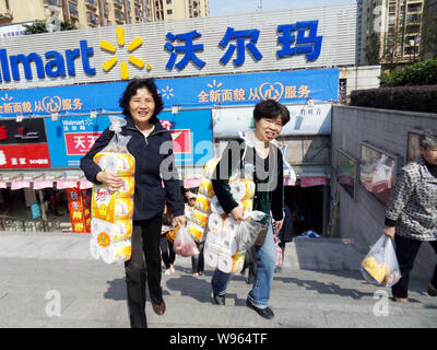 --FILE--Chinese customers carrying food and commodities walk out from a Walmart supermarket in Chongqing, China, 25 October 2011.   Wal-Mart Stores In Stock Photo