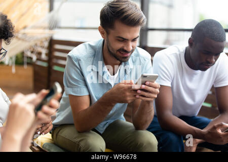 Diverse young people using smartphones hanging out together Stock Photo