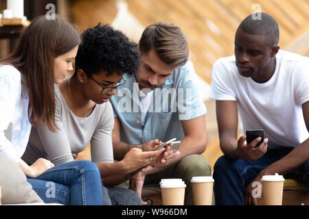 Diverse young people busy using smartphones together Stock Photo