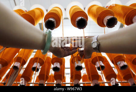 --FILE--A female Chinese worker handles the production of yarn on a spinning machine at the textile factory of Zhejiang Zhongding Textile Co., Ltd. in Stock Photo