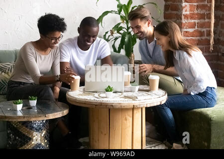 Happy diverse friends have fun watching funny video in caf Stock Photo