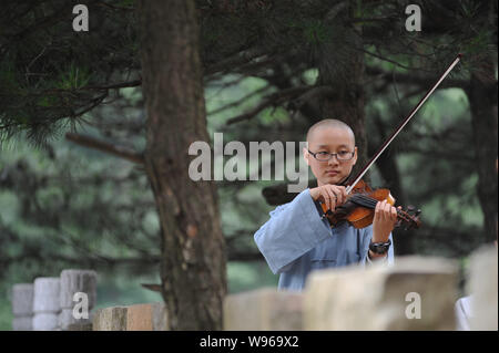 A Chinese Buddist nun of Guangxuan Art Troupe practices playing violin during a training session at Tiantai Temple on Tiantai Mountain in HongAn count Stock Photo