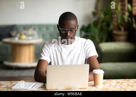 Focused black man studying on laptop drinking coffee Stock Photo