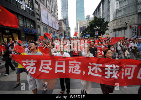 Chinese protestors wave Chinese national flags, hold up banners and shout slogans during an anti-Japan protest parade in Chongqing, China, 16 Septembe Stock Photo