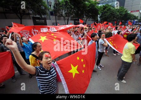 Chinese protestors wave Chinese national flags, hold up banners and shout slogans during an anti-Japan protest parade outside the Consulate-General of Stock Photo