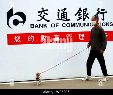 --File--A pedestrian walks his dog past an advertisement for Bank of Communications (BoCom) in Shanghai, China, 9 September 2011.   Bank of Communicat Stock Photo