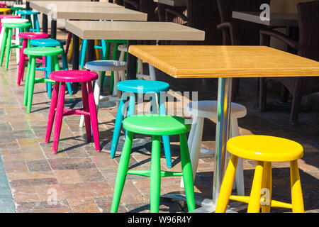 Bright and colorful interior of a cafe on a city street. The narrow street road is lined with stones that are painted with various colors. Stock Photo