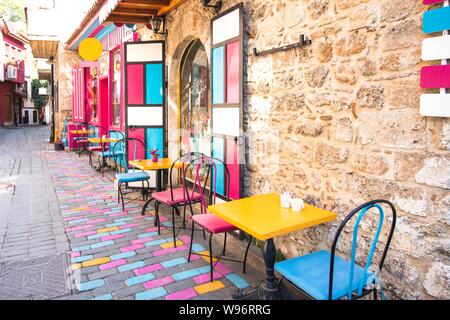 Bright and colorful interior of a cafe on a city street. The narrow street road is lined with stones that are painted with various colors. Stock Photo