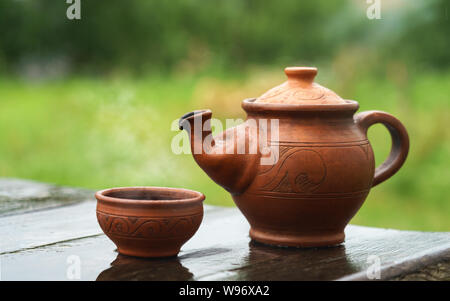 Clay hand made teapot and cup on wooden table outdoor Stock Photo