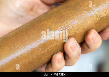 Close-up plumber hand holding used dirty rusty first-stage filter for drinking water. Changing cartridge of home sanitary equipment filtration system Stock Photo