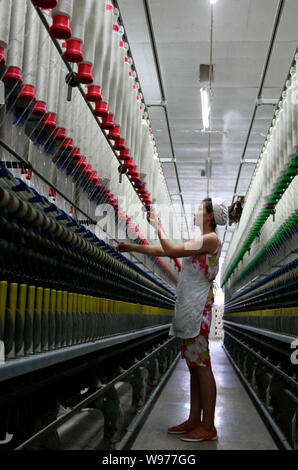 --FILE--A female Chinese worker handles the production of yarn to be exported to Southeast Asia on a spinning machine at a textile factory in Huaibei Stock Photo