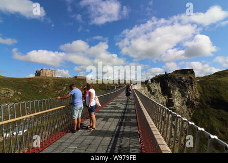 Tintagel, Cornwall, UK. 12th Aug, 2019. People on the controversial new footbridge re-connecting both halves of Tintagel Castle for the first time in 500 years, has at long last been opened. The medieval castle on the Cornwall coast - long rumoured to be the site of King Arthur's legendary Camelot - lost its original bridge sometime between the 15th and 16th centuries. A storm which hit the Cornish coast delayed the bridge's opening. Credit: Keith Mayhew/SOPA Images/ZUMA Wire/Alamy Live News Stock Photo