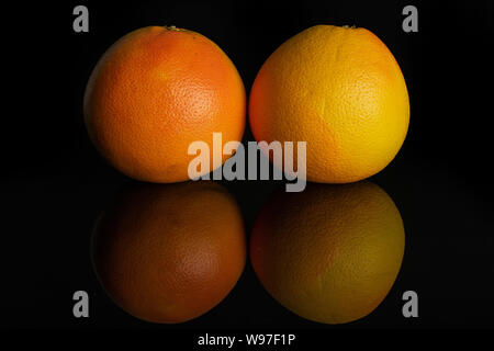 Group of two whole fresh pink grapefruit isolated on black glass Stock Photo