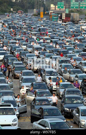 Chinese holidaymakers rest next to their cars as they are waiting in a long queue in a traffic jam on an expressway during the Mid-Autumn Festival and