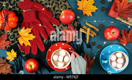 Autumn Fall theme flatlay overhead with cups of hot chocolate, spices and marshmallows on scattered maple leaves background. Stock Photo