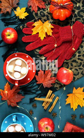 Autumn Fall theme flatlay overhead with cups of hot chocolate, spices and marshmallows on scattered maple leaves background. Stock Photo