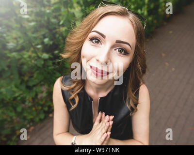 Photo of attractive young female model with pleading expression, asks to help her in difficult situation, has helpless look, poses against nature back Stock Photo