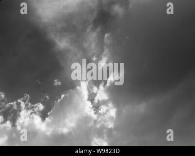Monochrome of clouds with sunlight shining dramatically through them Stock Photo