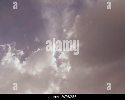 Sepia effect of clouds with sunlight shining dramatically through them, illuminating the sky Stock Photo