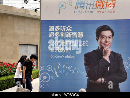 --FILE--Local residents walk past an advertisement with the image of Kaifu Lee, former president of Google China, for t.QQ.com, the Twitter-like micro Stock Photo