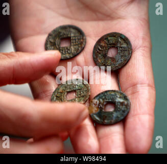 A Chinese archaeologist shows the bronze coins unearthed from a tomb of Tang Dynasty (AD 618-907) in Xinzhuang village, Pingle town, Mengjin county, L Stock Photo