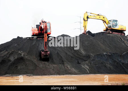 --FILE--Excavators transport iron ore at the Port of Qingdao in Qingdao city, east Chinas Shandong province, 7 September 2011.   China is trying to in Stock Photo