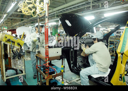 Chinese factory workers assemble Toyota cars on the assembly line at an auto plant of FAW-Toyota, a joint venture between FAW and Toyota, in Tianjin, Stock Photo