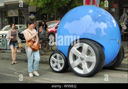 Local residents look at a concept car of Volkswagens Peoples Car Project on Gulou East Street in Beijing, China, 21 June 2011.   German carmaker Volks Stock Photo