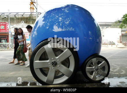 Local residents look at a concept car of Volkswagens Peoples Car Project on Gulou East Street in Beijing, China, 21 June 2011.   German carmaker Volks Stock Photo