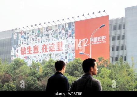 --FILE--Chinese men walk past a huge billboard of Alibaba at the headquarters of Alibaba Group in Hangzhou city, east Chinas Zhejiang province, 16 Sep Stock Photo