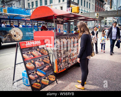 A girl looks at the menu of a Japadog hot dog trailer stand on West Cordova Street in Vancouver, British Columbia, Canada. Stock Photo