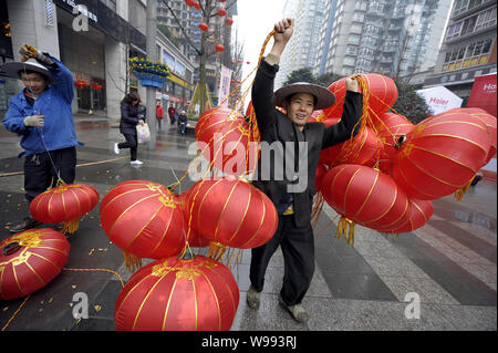 Chinese workers carry red lanterns to be hung up on the trees along a shopping street in preparation for the upcoming Spring Festival, known as the Ch Stock Photo