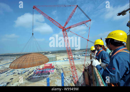 Workers watch the dome of the containment structure for the No.1 ...
