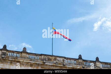 Yellow, blue and red striped Colombian flag flies above a government building in Bogotá, Colombia on a sunny summer day Stock Photo