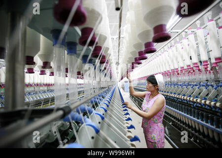 --FILE--A female Chinese worker handles the production of yarn to be exported to the United States and Europe on a spinning machine at a textile facto Stock Photo