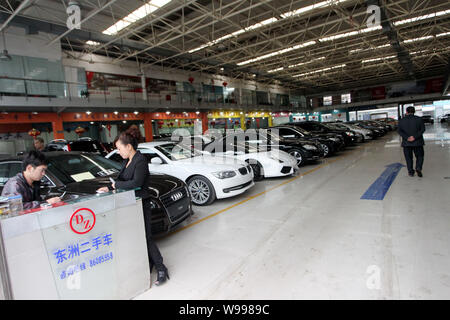 A Chinese car buyer walks past rows of used luxury cars at a second-hand car market in Wenzhou city, east Chinas Zhejiang province, 16 November 2011.