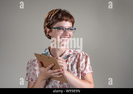 BOSSIER CITY, LA., U.S.A.. - AUG. 8, 2019: A pretty, gracious-looking young woman smiles at an unseen person as she makes notes on a clipboard in a st Stock Photo