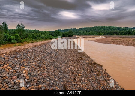 Gabion, Cages Filled with Rocks Placed at Riverbank to Control Erosion, Background of Dark Sky and River dirty water, after rain in rainy season lands Stock Photo