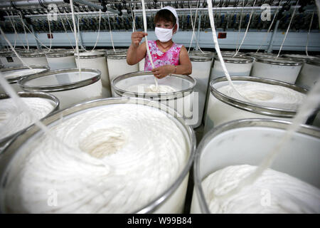 --FILE--A female Chinese worker handles the production of yarn to be exported to the United States and Europe on a spinning machine at a textile facto Stock Photo