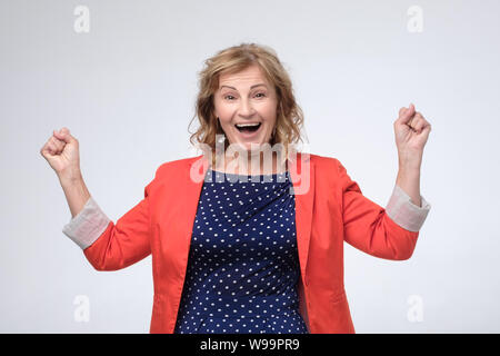 Mature lucky european woman being excited and happy keeping fists up. Stock Photo