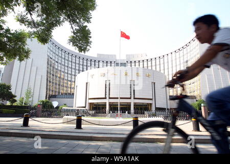 --FILE--A Chinese cyclist rides past the headquarters of the Peoples ...