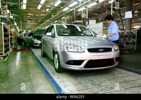 Chinese factory workers assemble Ford Focus cars on the assembly line ...