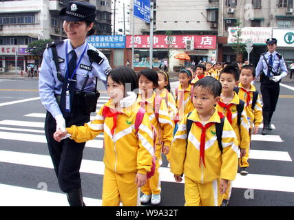 Chinese policewomen escort pupils across the street to their primary school in Changsha city, central Chinas Hunan province, 12 May 2010.   China is s Stock Photo