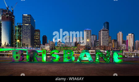 From  the illuminated 'Brisbane' artwork at Southbank Parklands, Brisbane, Australia, the lights of the city are switching on as night falls. Stock Photo
