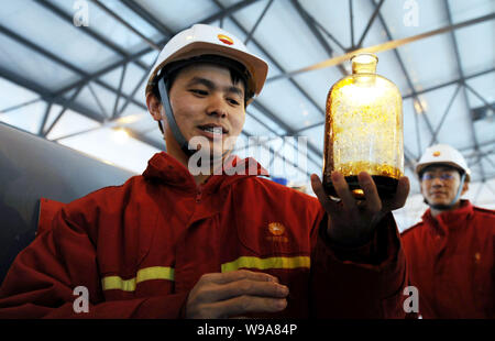 A Chinese worker from CNPC (China National Petroleum Corporation) shows a bottle of crude oil sampled from the oil pipe at the terminal of the China-R Stock Photo