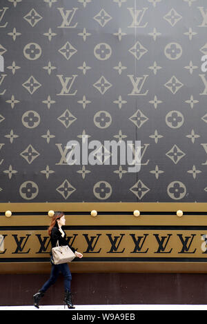 A trendy young woman carrying a Louis Vuitton (LV) handbag walks past a  huge LV suitcase outside the Plaza 66 shopping mall in Shanghai, China, 4  Nove Stock Photo - Alamy