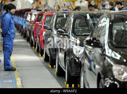 Chinese factory workers look at Roewe 350 cars going through the assembly line at the auto plant of SAIC in Nanjing city, east Chinas Jiangsu province Stock Photo